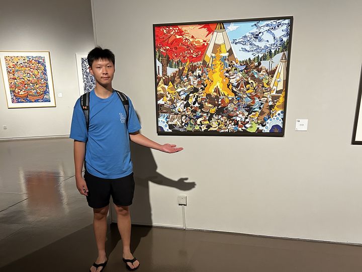 Alex beside a farmers' painting at the exhibition